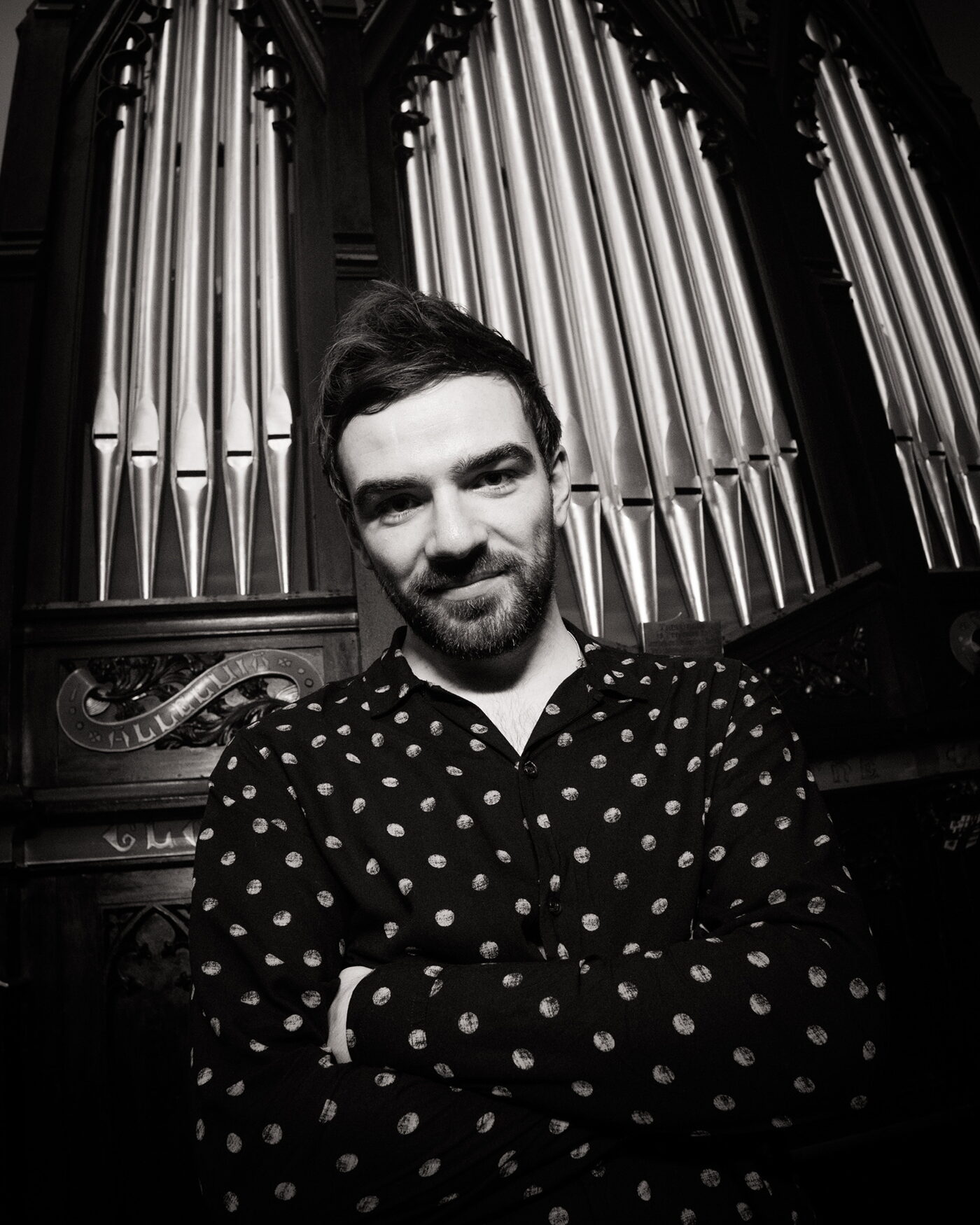 Brían Farrell, founding artist of Song Boat, photographed before the pipes of a church organ
